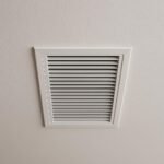 Close-up of a white rectangular ducted vent installed on a modern ceiling